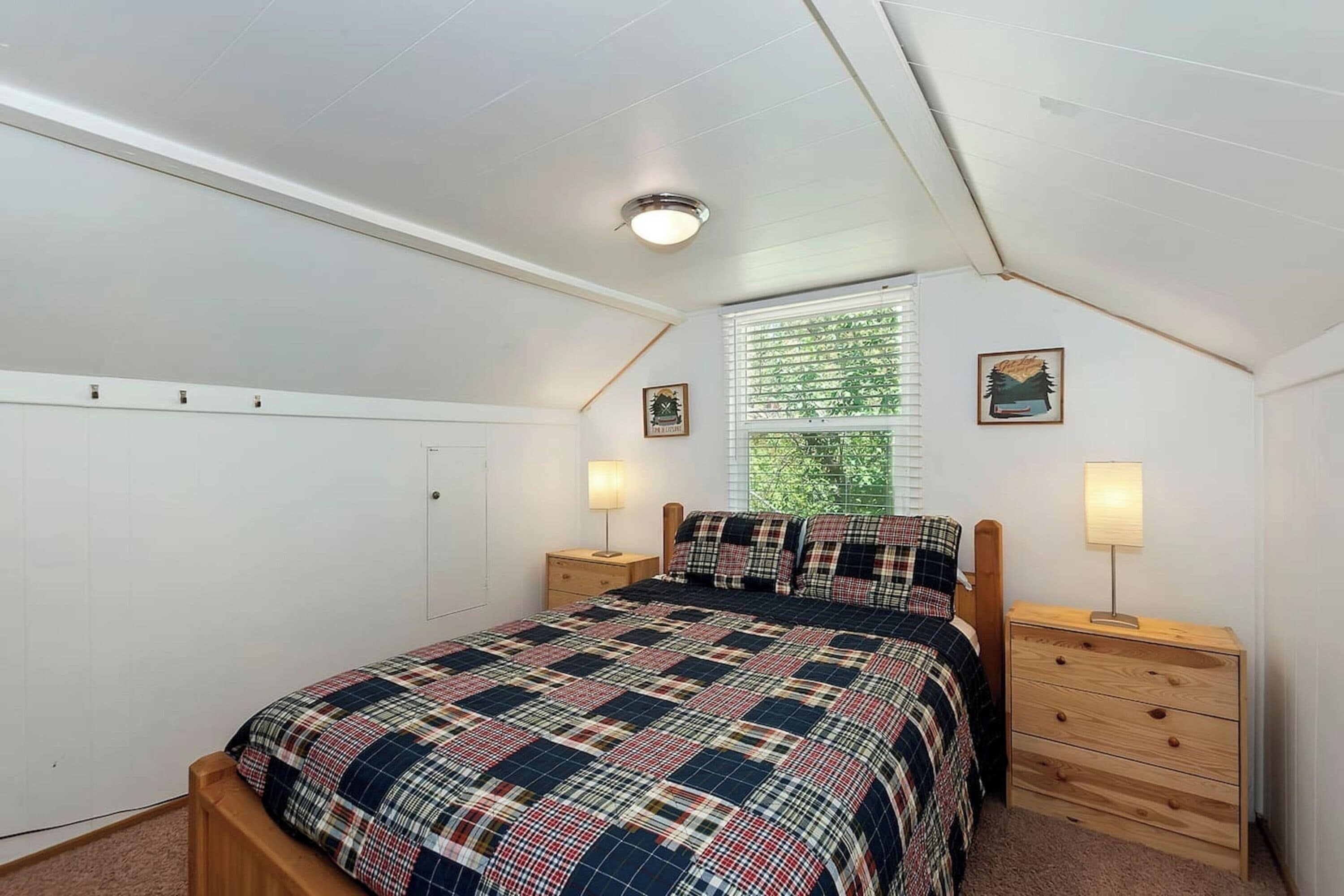 Una camera da letto con un letto, due comodini, una finestra con tende e una lampada a soffitto.