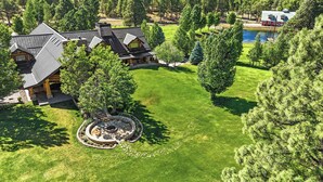 A large, multi-story log cabin with a stone foundation and a wrap-around porch. - Legacy Lodge & Barn Retreat, Sleeps 42 (Heber)