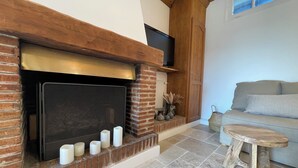 Una chimenea con varias velas, un televisor montado encima y un sofá en la habitación contigua.