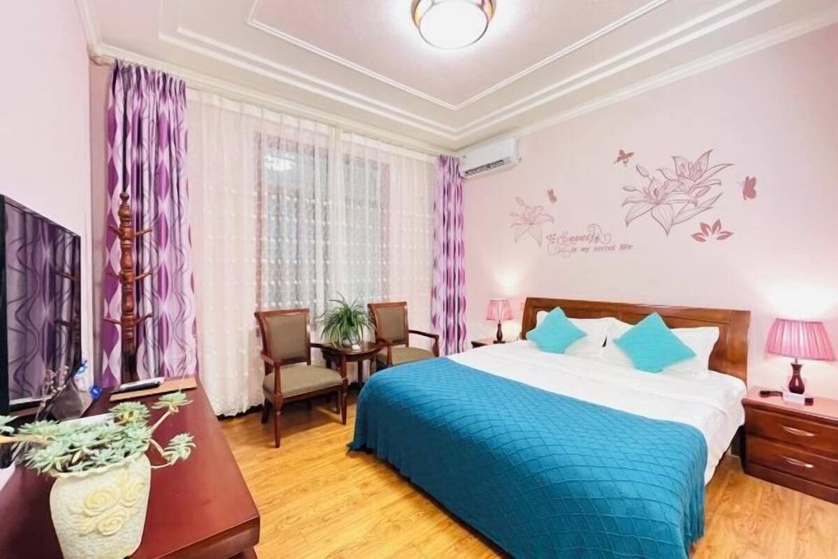 A bedroom with a bed, a desk, a chair, a TV, and a wall decoration.