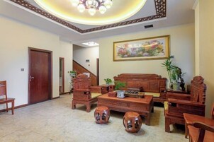A spacious living room with a wooden sofa set, a coffee table, and a staircase leading to another level.
