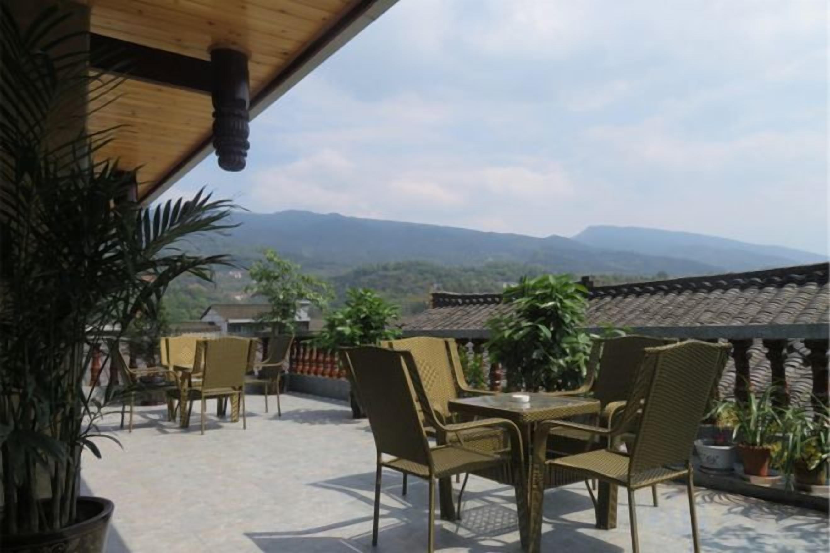 Un área de estar al aire libre con sillas de mimbre y una mesa, con vistas a un paisaje montañoso.