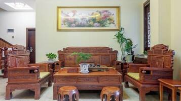 Un conjunto de mobiliario de madera tradicional que incluye un sofá, dos sillones y una mesa de centro, dispuesto en un salón con un cuadro floral grande en la pared.
