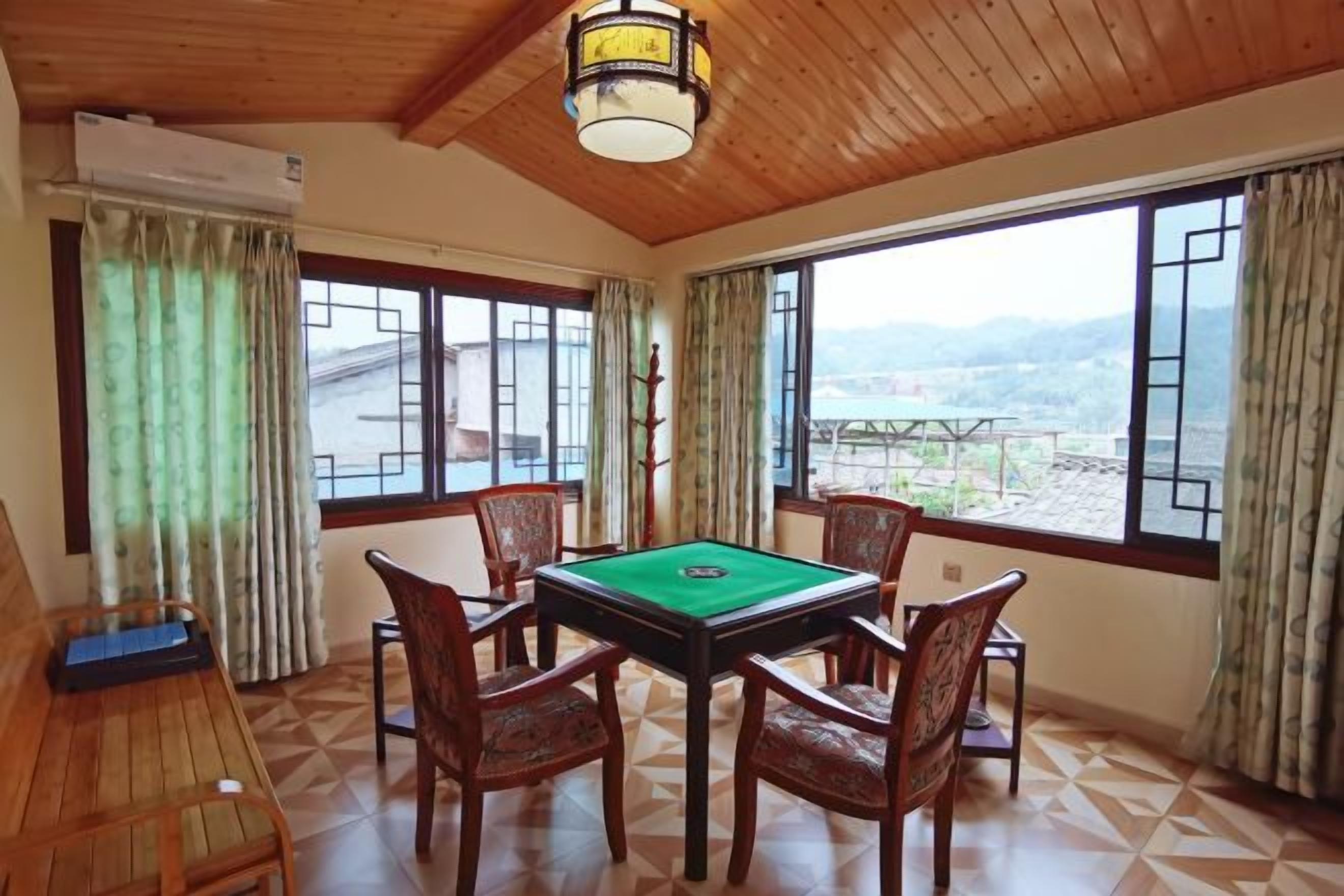 Una habitación con mesa de billar, sillas de madera y grandes ventanales que ofrecen vistas al exterior.