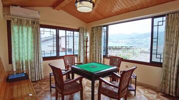 Una habitación con mesa de billar, sillas de madera y grandes ventanales que ofrecen vistas al exterior.
