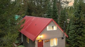Une petite cabane à toit rouge, entourée d’une forêt dense.