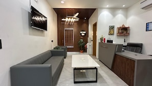 Et moderne receptionsområde med sofa, receptionistskranke, et fladskærms-tv og en loftsvifte.