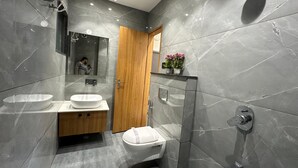 Et moderne badeværelse med et stort spejl, to håndvaske, et toilet og en bruseniche.