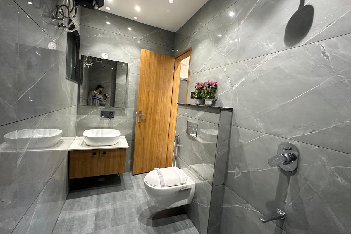 Ein modernes Badezimmer mit einem großen Spiegel, zwei Waschbecken, einer Toilette und einer Dusche.