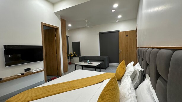 Et moderne hotelværelse med seng, sofa, fjernsyn og skrivebord.