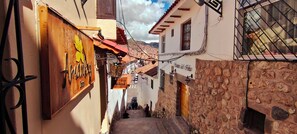 A narrow street with stone buildings, wooden doors, and a sign for 'Almaviva'. - Amankay hotel cusco (Cusco)