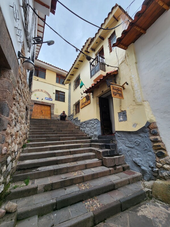 A set of stone steps leading to a building with a sign reading "Junquey Hospedaje."