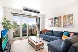 Relax in this stylish living room with a sofa, coffee table, and city views through the sliding glass door.
