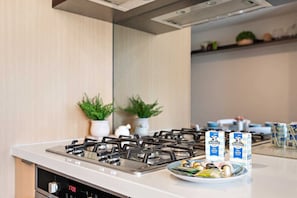A kitchen with a gas stove, two potted plants, and Devondale Full Cream milk cartons on the counter.