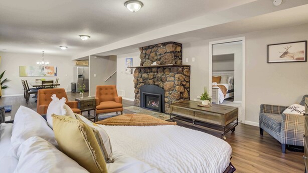 A spacious living room with a stone fireplace, a large bed with multiple pillows, and a dining area with a table and chairs. - Mountain Villa! Scenic Getaway with Hot Tub (Cascade-Chipita Park)