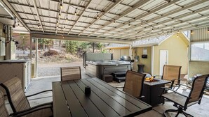 An outdoor patio area with a hot tub, seating, and a covered roof. - Mountain Villa! Scenic Getaway with Hot Tub (Cascade-Chipita Park)