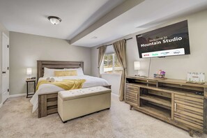 Un dormitorio con cama, mesitas de noche, un televisor mostrando un mensaje de bienvenida y un escritorio con ordenador.