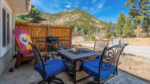 An outdoor patio with a table and chairs, a grill, and a wooden fence. - Mountain Studio! Cozy Escape with Stunning Views (Cascade-Chipita Park)