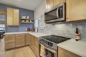 A modern kitchen with wooden cabinets, a stainless steel microwave, a built-in oven, and a glass stovetop.