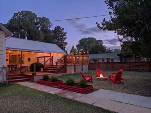 A backyard with a covered patio, outdoor seating, a fire pit, and a wooden deck.