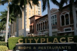 A sign for Cityplace with the text "Shops & Restaurants" indicating a commercial area. - Downtown WPB Condo at Cityplace (West Palm Beach)