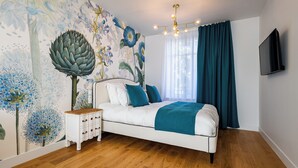 A bedroom with a white bed, teal bedding, a wooden nightstand, and a wall mural. - Solstice Beaune - Hotel et Terroir (Beaune)