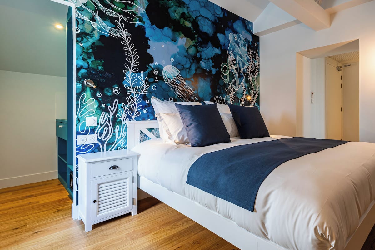 Ein Schlafzimmer mit einem Bett, einem weißen Nachttisch und einer Wandmalerei.