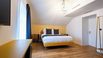 Un dormitorio moderno con una cama de madera, una mesita de noche y una pequeña cómoda, además de un televisor montado en la pared.