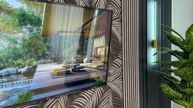 A modern living room with a large flat-screen TV mounted on a wall with a leaf-patterned wallpaper.