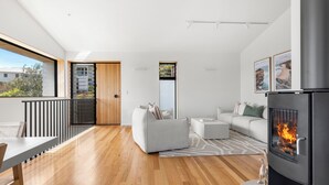 Un salon moderne doté d’une cheminée, d’un canapé, d’un coin repas et offrant une vue sur l’extérieur.
