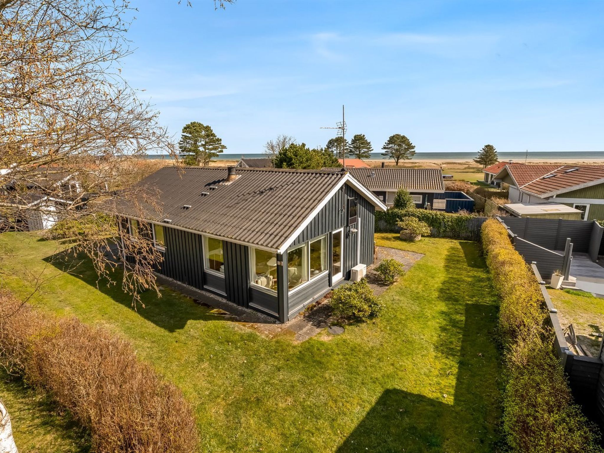 Een modern huis met een schuin dak, grote ramen en een verzorgd gazon.