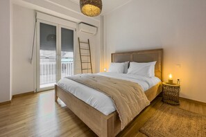 A bedroom with a wooden bed, white bedding, a small bedside table with a candle, a ladder, and a view through a large window. - Phaedrus Living: Kallithea Heights Residence (Kallithea)