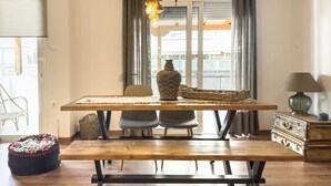 A dining area with a wooden table, two chairs, a bench, a vase, a lamp, and a suitcase. - Phaedrus Living: Kallithea Heights Residence (Kallithea)