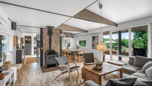 A modern interior with a fireplace, dining area, and large windows offering views of greenery. - "Fatima" - 1km from the sea by Interhome (Fanø)