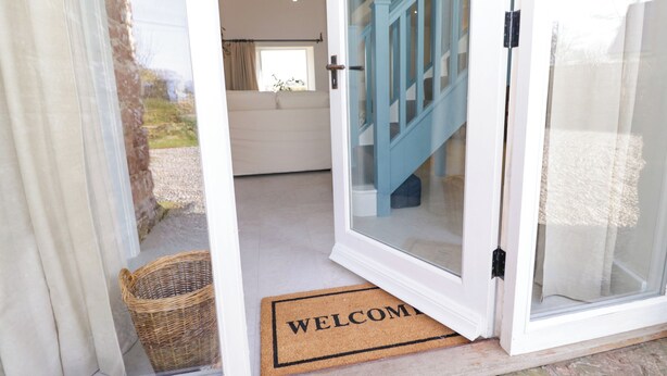 A doorway with a 'WELCOME' mat leading to a staircase. - The Roost (Carlisle)