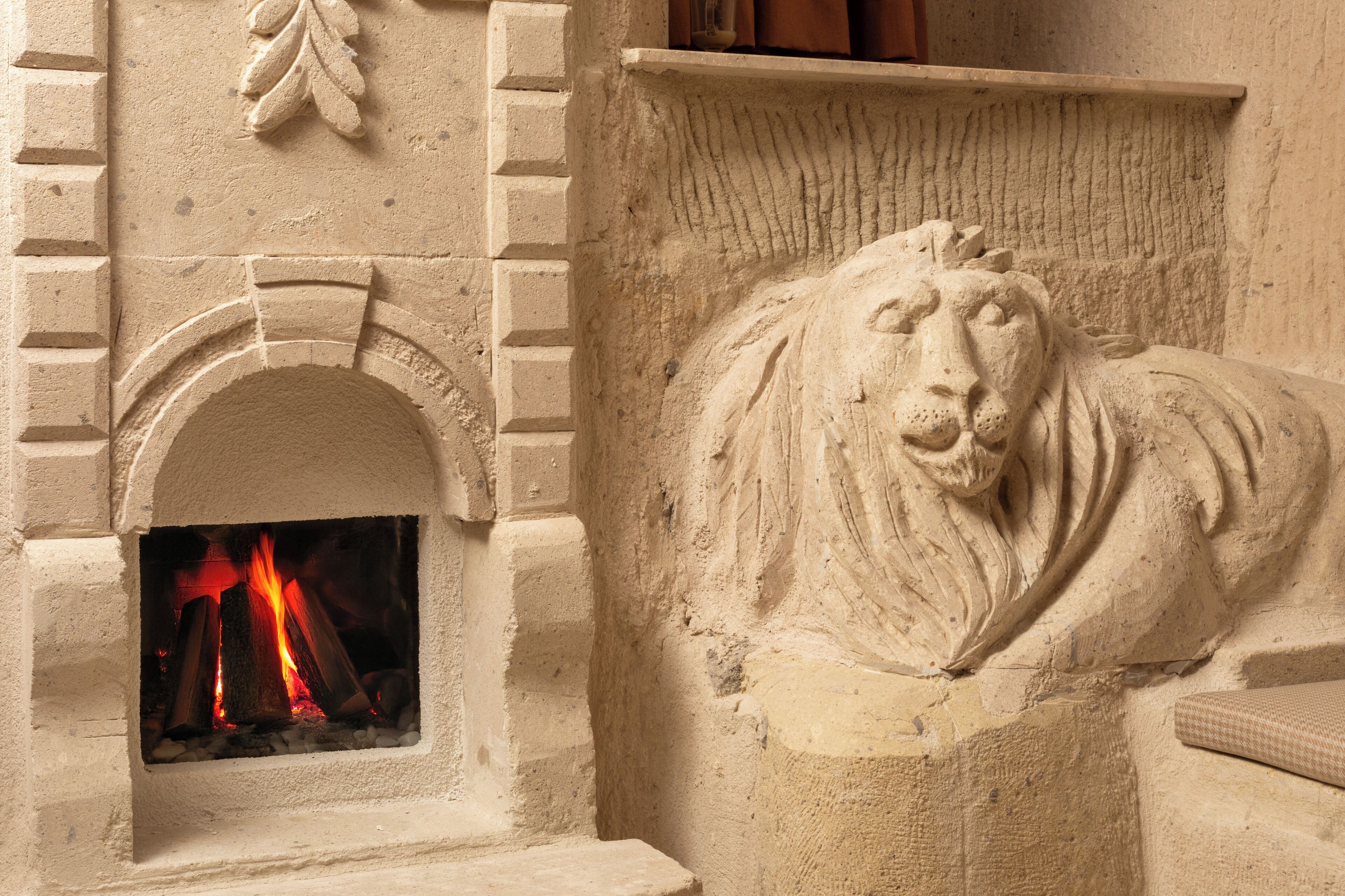 A fireplace with a lion sculpture and a brick wall.