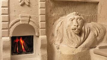 A fireplace with a lion sculpture and a brick wall.