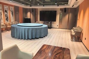 Una sala de conferencias con una mesa redonda, sillas, una pantalla grande y una mesa de madera.