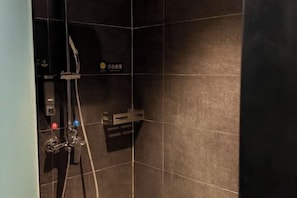 A shower area with dark tiles, a handheld showerhead, and a control panel. - Shanyehong Hotel (Beijing)