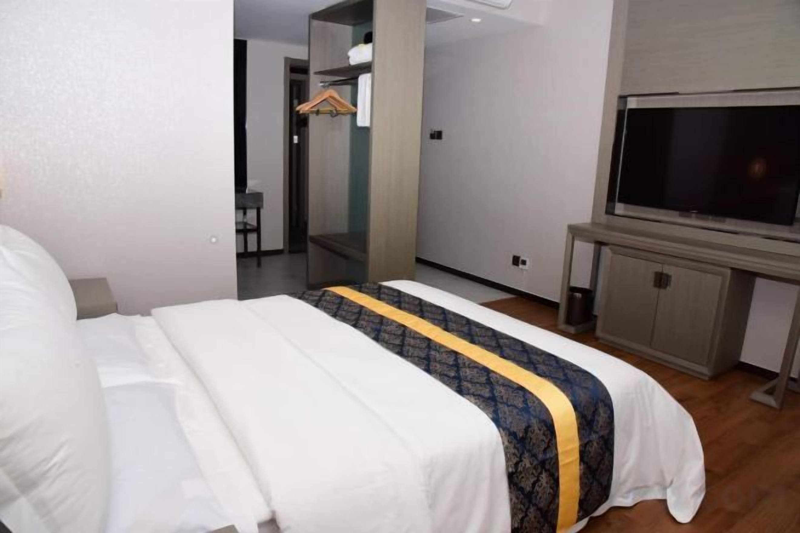 A hotel room with a bed, a television, and a wardrobe.