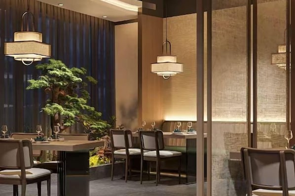 A restaurant interior with tables, chairs, pendant lighting, and a large plant. - Shanyehong Hotel (Beijing)