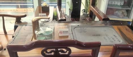 A wooden table with a metal tray, a glass container, and a menu.