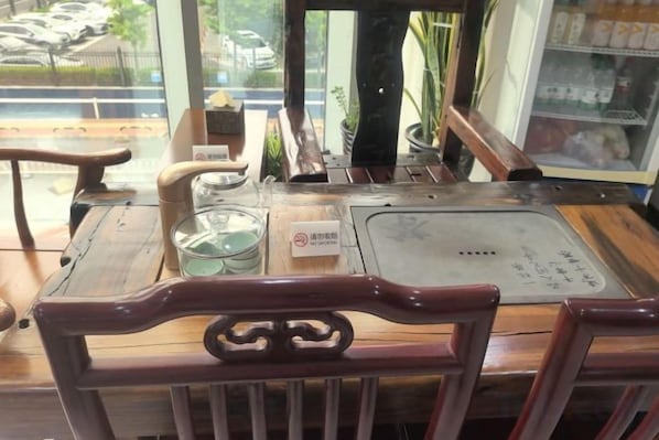 A wooden table with a metal tray, a glass container, and a menu.
