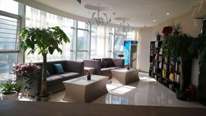 A modern living room with a sofa, coffee table, and a bookshelf filled with books. - Shanyehong Hotel (Beijing)