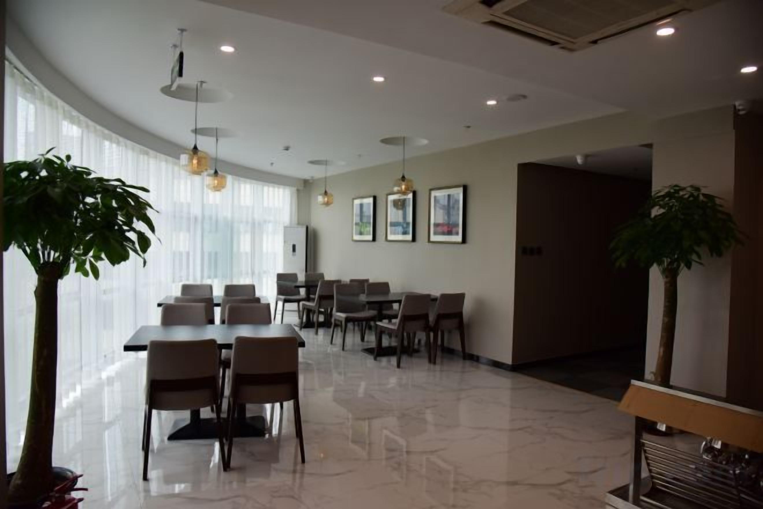 Un salón de conferencias moderno en un hotel, con una gran mesa, varias sillas y una planta en maceta.