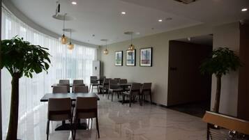 A modern hotel conference room with a large table, multiple chairs, and a potted plant.