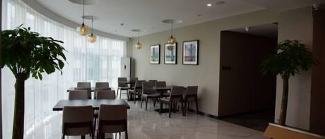 A modern hotel conference room with a large table, multiple chairs, and a potted plant.