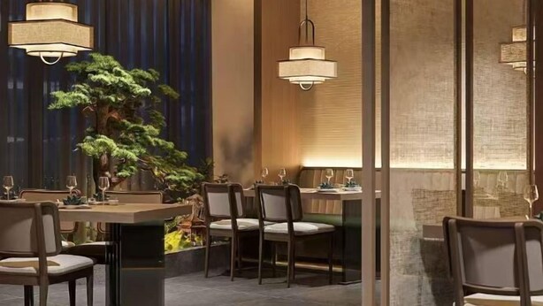 A modern dining area with a large table set for a meal, surrounded by chairs. There are hanging pendant lights above the table, and a large potted plant is visible to the left. - Shanyehong Hotel (Beijing)