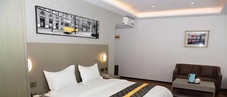 A hotel room with a bed, bedside tables, a sofa, and artwork on the walls.
