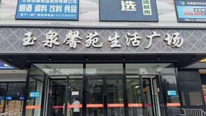 A storefront with a large sign in Chinese characters, glass doors, and a pedestrian walkway. - Shanyehong Hotel (Beijing)